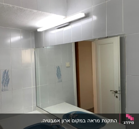 מראה גדולה מעל כיור בחדר אמבטיה